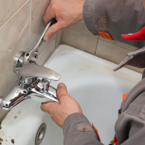 A residential plumber repairs a bathtub faucet.