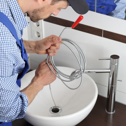 Residential plumber unclogs a drain.