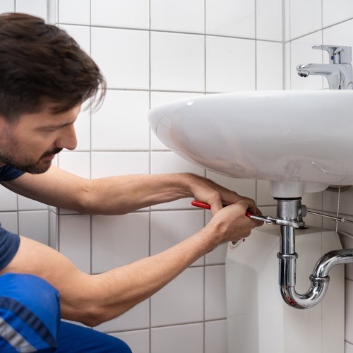 A residential plumber fixes a sink.
